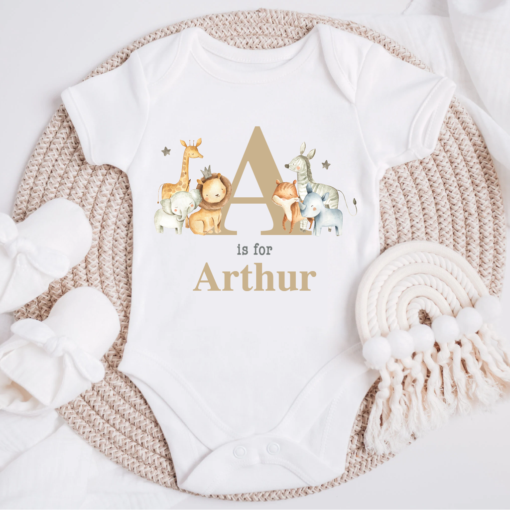 Personalised baby jungle safari animal vest in beige mocha, featuring an initial and name' design with adorable illustrations of a giraffe, lion, fox, elephant and zebra on a white bodysuit. Perfect for newborns to 12 months.
